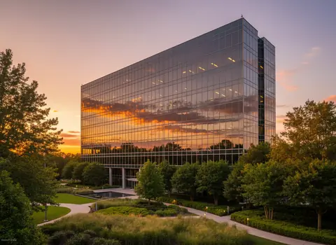 A modern glass office building at sunset