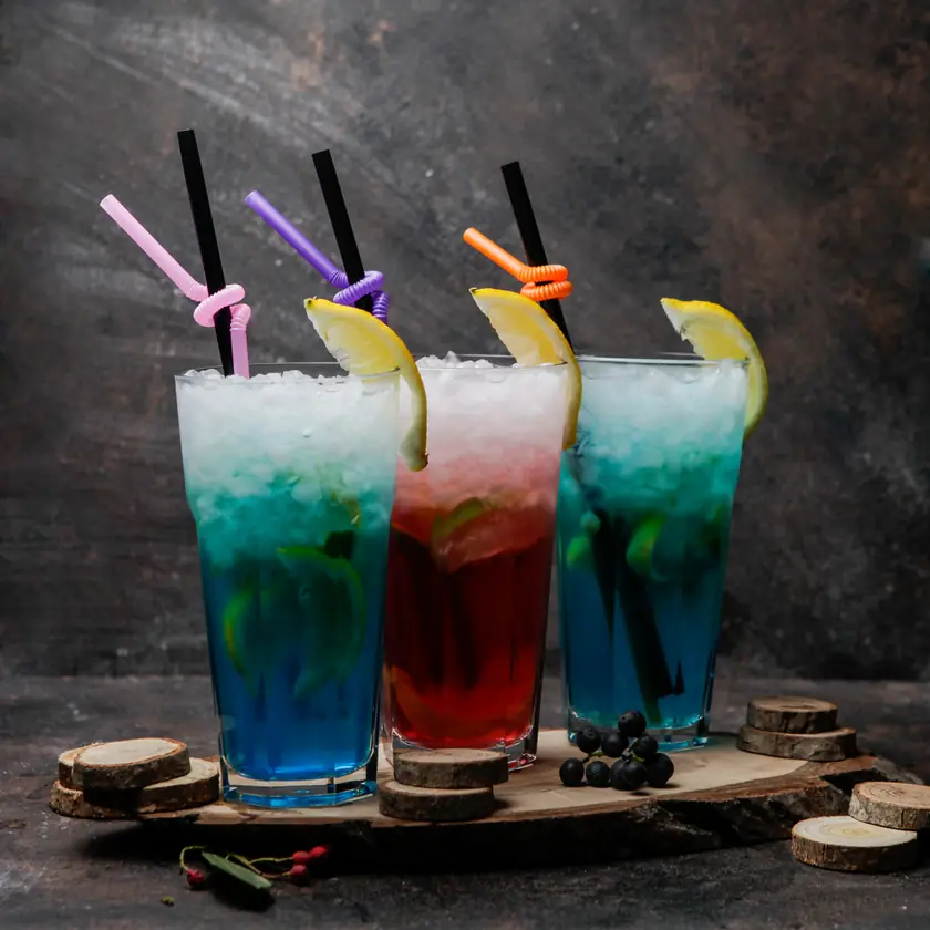 Three layered iced drinks with straws and lemon slices