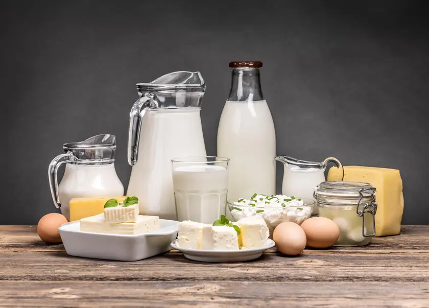 Milk bottles, cream and cheese on a wooden table